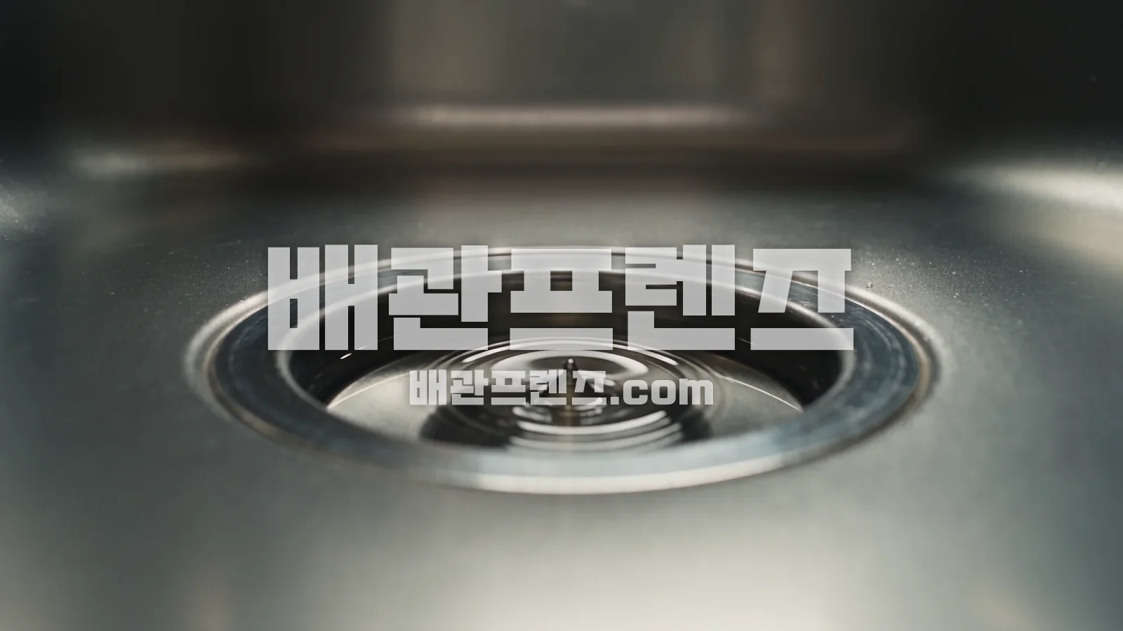 물방울이 떨어지는 스테인리스 싱크대 배수구