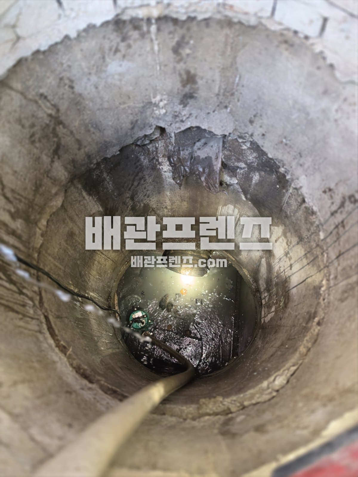 맨홀 바닥 관로에 호스를 넣어 작업하는 모습