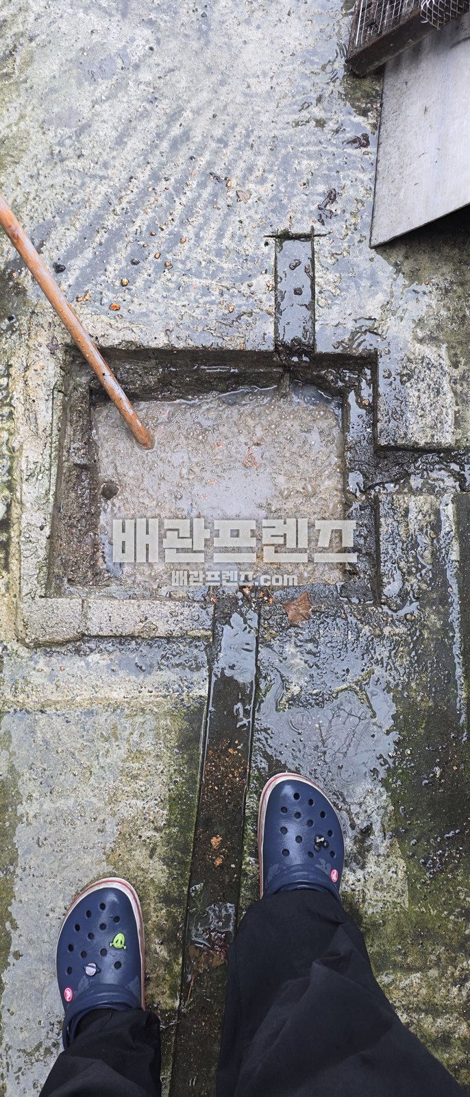 외부 배수로 덮개를 열고 찌꺼기를 확인하는 모습