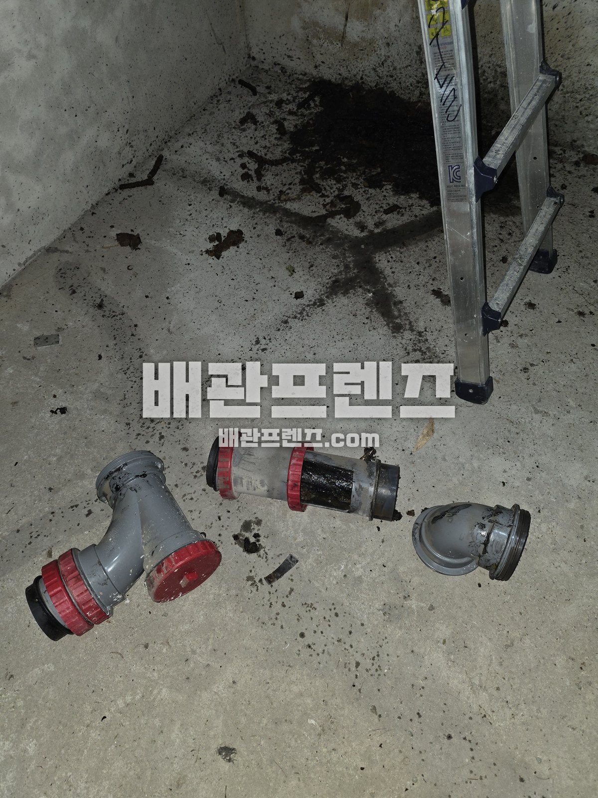 바닥에 떼어 둔 배관 부속과 검은 찌꺼기