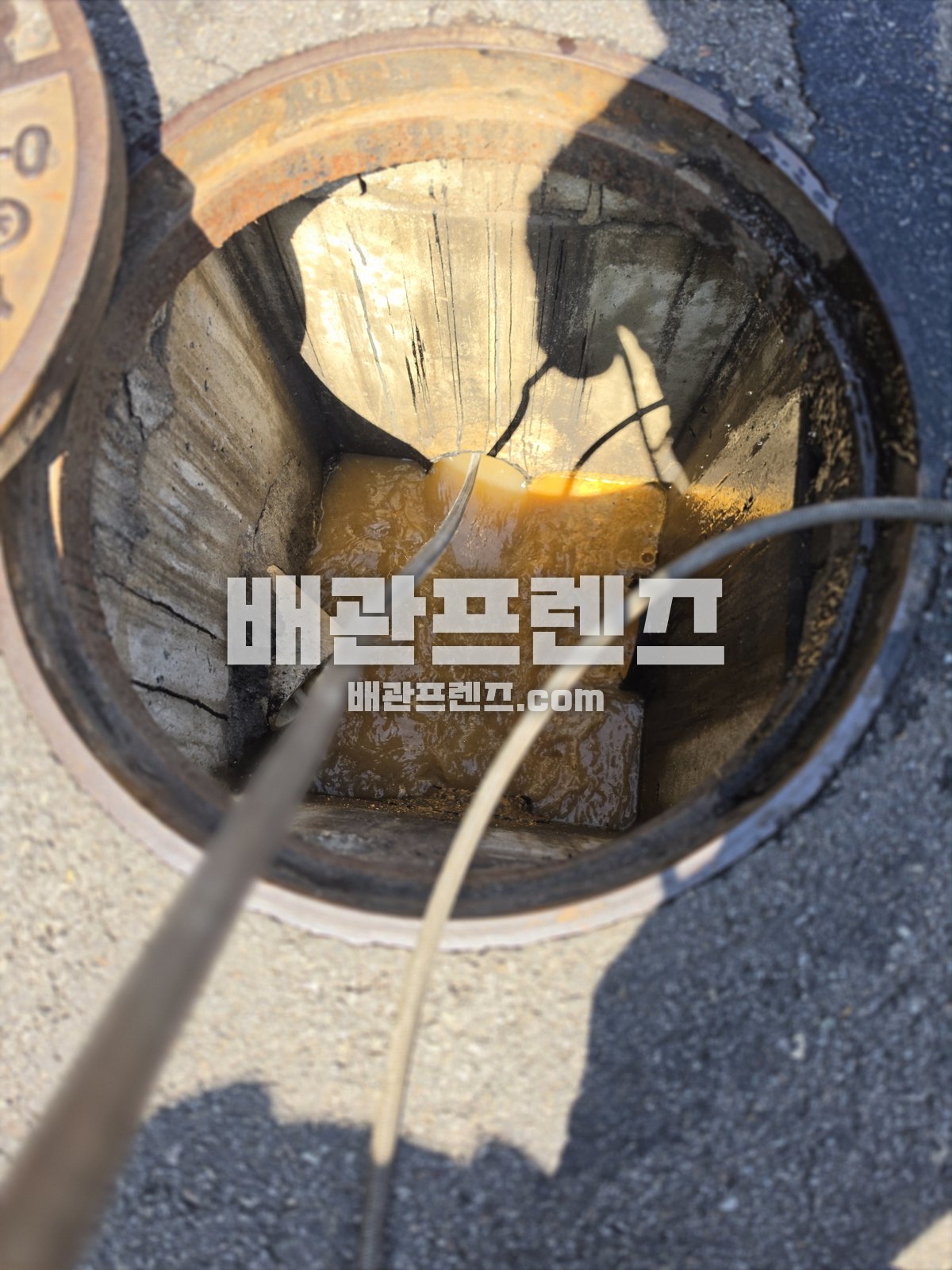 열어 둔 맨홀 안으로 장비 줄을 넣은 모습