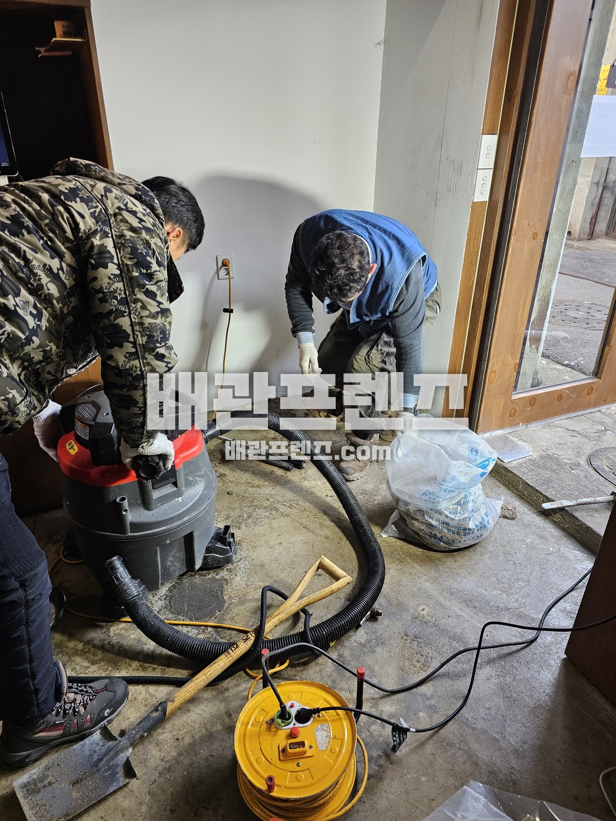 바닥 배수구를 열어 트랩과 배수관 입구를 점검하는 장면