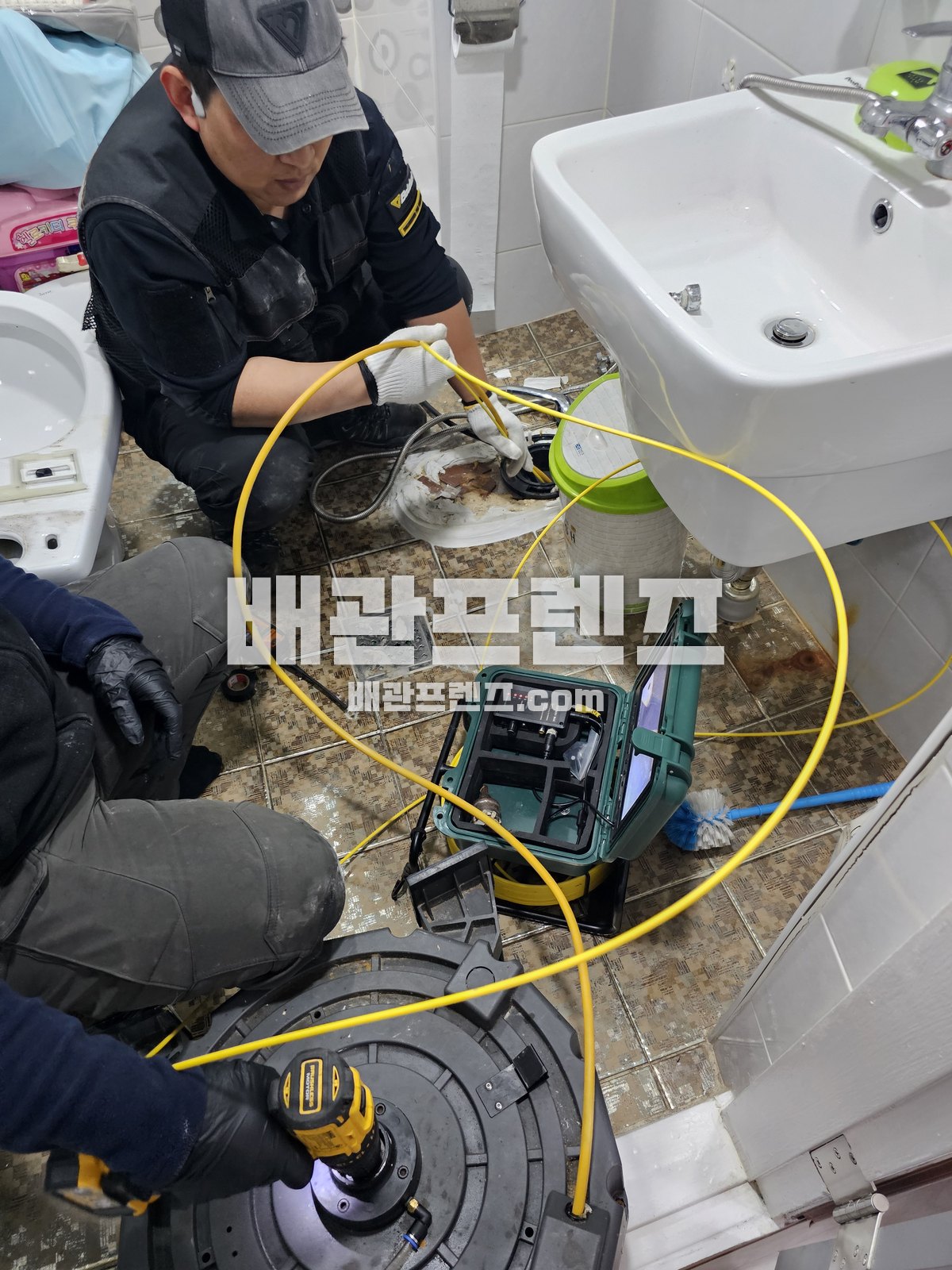 바닥 배수구를 열어 트랩과 배수관 입구를 점검하는 장면