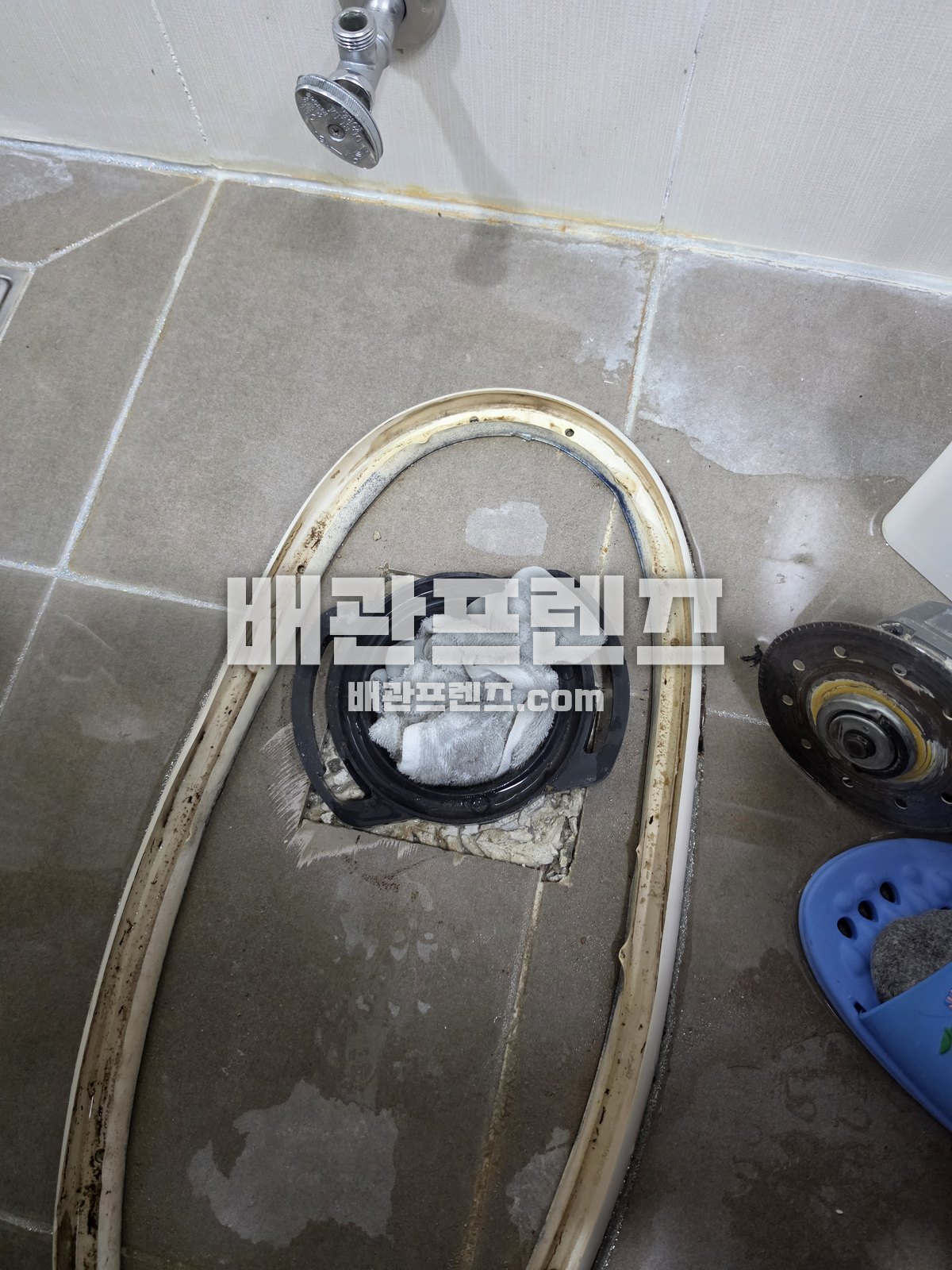 변기를 분리한 바닥의 연결 부속과 천으로 덮인 배관 입구