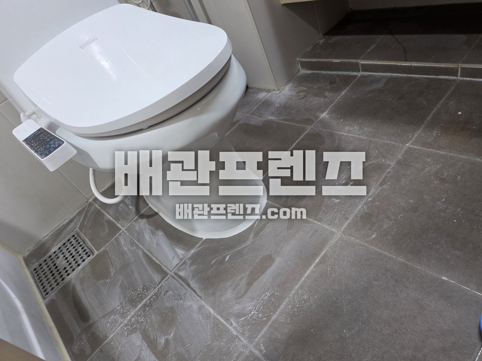 욕실 바닥에 설치된 비데 변기와 바닥 배수구